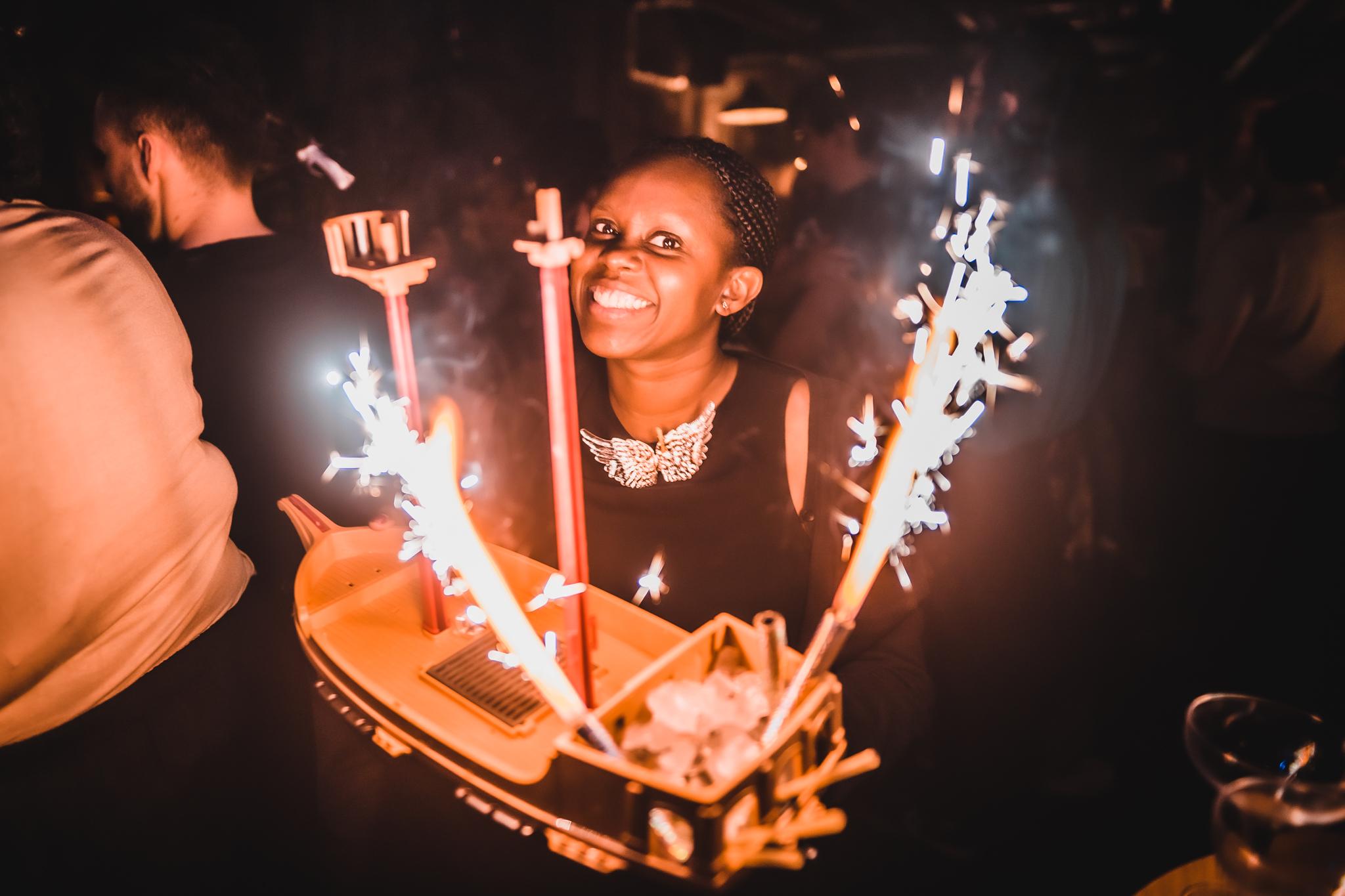 Girl holding a cocktail sharer with sparklers in the shape of a ship